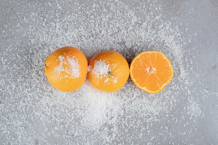 Foto gratuito naranjas jugosas que se sientan en polvo de coco esparcido sobre la mesa de mármol.