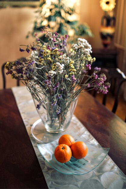 Naranjas junto a un jarrón con flores