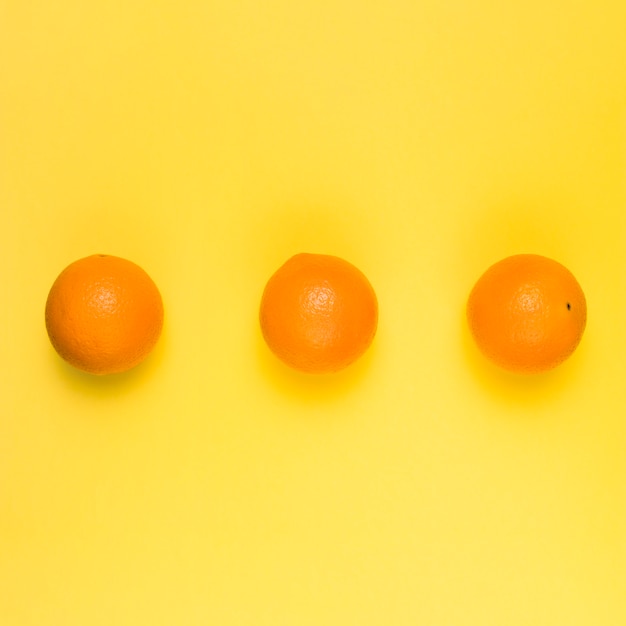 Naranjas maduras brillantes sobre fondo amarillo