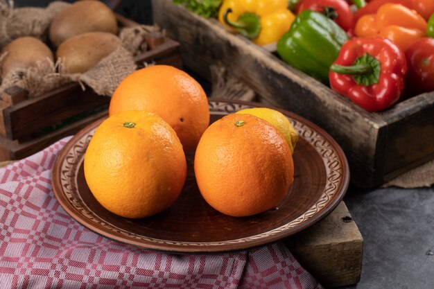 Naranjas en un plato y pimientos alrededor