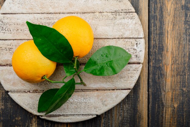 Naranjas con rama en madera y tabla para cortar