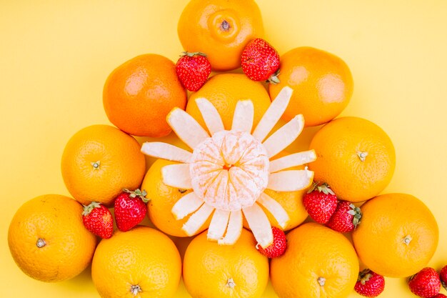 Naranjas triangulares con fresas sobre fondo amarillo