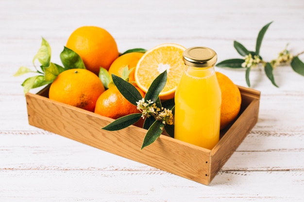 Naranjas y zumo en caja de madera.