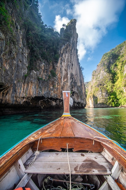 Nariz de barco tradicional de cola larga de madera con decoración de flores y cintas en la playa de Maya Bay contra empinadas colinas de piedra caliza. Fondo de atracción turística principal de Tailandia, isla de Ko Phi Phi Leh