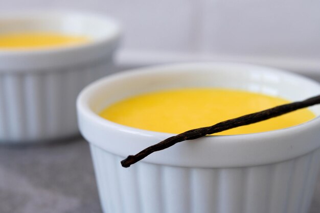 Natillas de vainilla caseras en lazo blanco sobre fondo de piedra gris