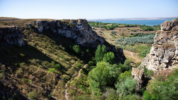 Naturaleza de Moldavia, desfiladero con pendientes rocosas, frondosos árboles y ruta de senderismo en el fondo