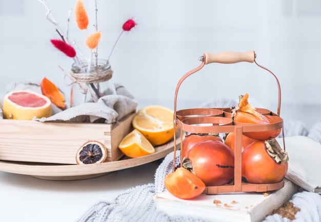 Naturaleza muerta caqui fresco en una canasta sobre una mesa para servir preparación para el desayuno concepto de celebración