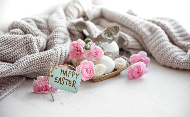 Naturaleza muerta con huevos de Pascua, flores frescas y la inscripción Feliz Pascua en la postal