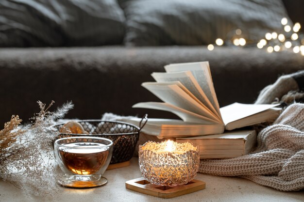 Naturaleza muerta con una taza de té, libros y una vela encendida en un hermoso candelero. Concepto de confort en el hogar.