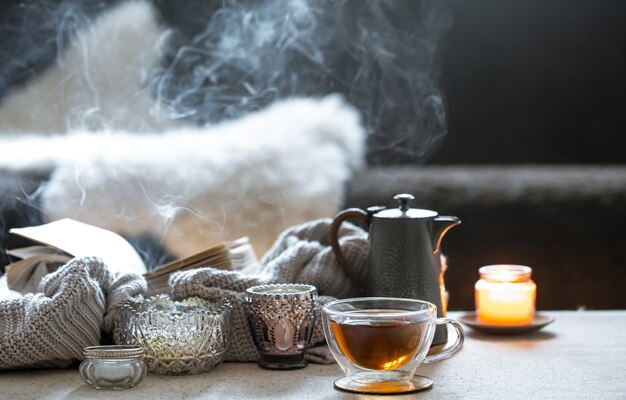 Naturaleza muerta con una taza de té, una tetera y hermosos candelabros vintage con velas sobre un fondo borroso.