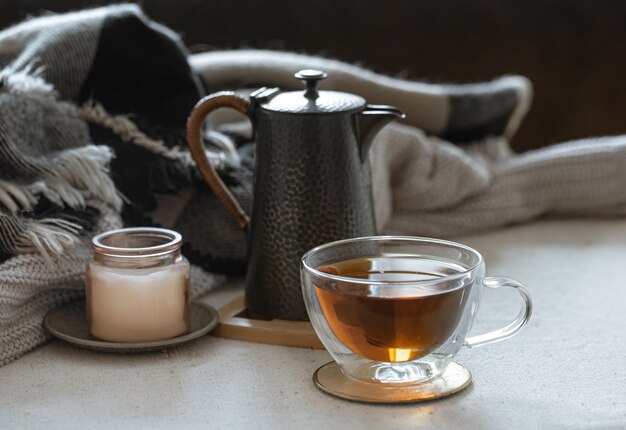 Naturaleza muerta con una taza de té, una tetera, un libro y detalles decorativos