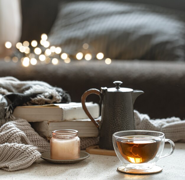 Naturaleza muerta con una taza de té, una tetera, libros y una vela en un candelabro