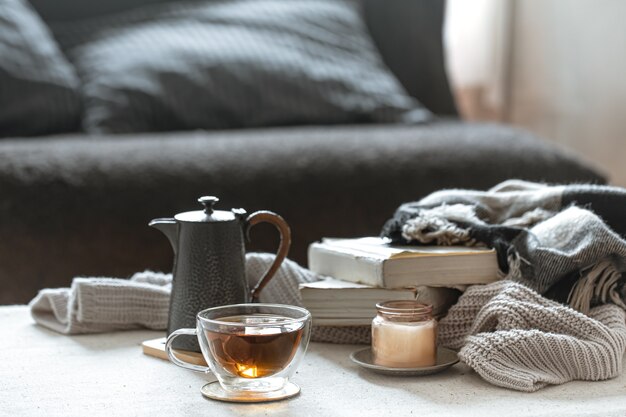 Naturaleza muerta con una taza de té, una tetera, libros y una vela en un candelero. Concepto de confort en el hogar.