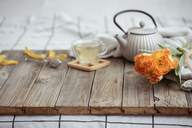 Foto gratuita naturaleza muerta con una taza de té, una tetera y un ramo de tulipanes