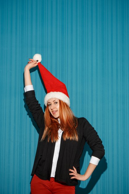 Navidad divertida niña con un gorro de Papá Noel en el fondo azul del estudio
