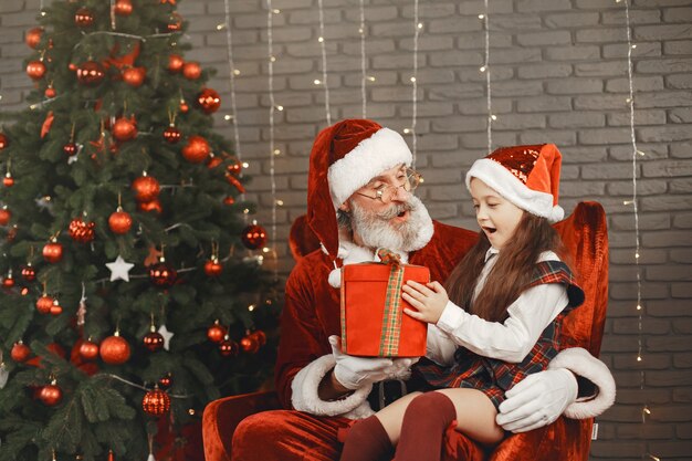 Navidad, niño y regalos. Santa Claus le trajo regalos al niño. Niña alegre abrazando a Santa.
