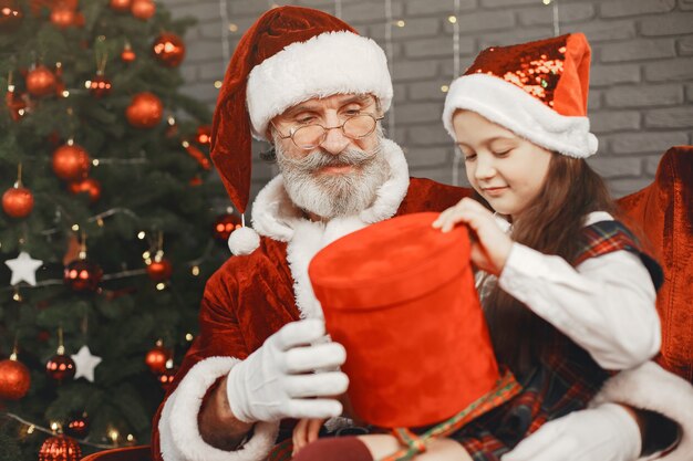 Navidad, niño y regalos. Santa Claus le trajo regalos al niño. Niña alegre abrazando a Santa.