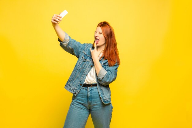 Necesita ropa mínima para selfie. Retrato de mujer caucásica en espacio amarillo