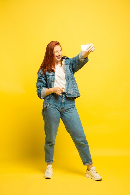 Necesita ropa mínima para selfie. Retrato de mujer caucásica en espacio amarillo