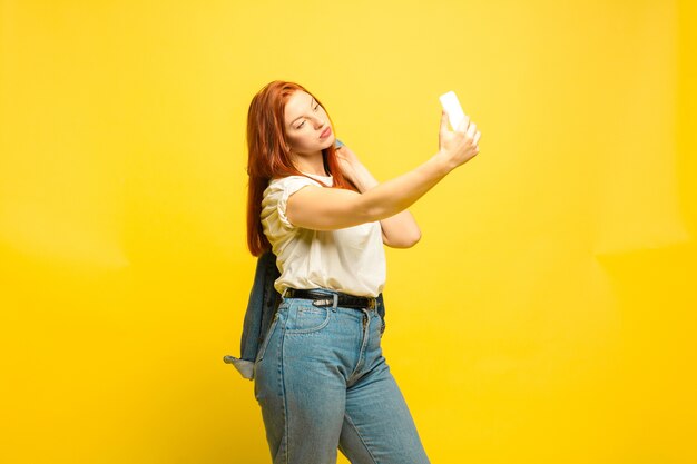 Necesita ropa mínima para selfie. Retrato de mujer caucásica en espacio amarillo