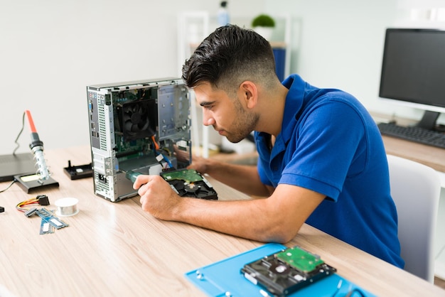 Necesito arreglar esto. Joven usando un destornillador para mirar dentro de una computadora CPU rota antes de repararla en la tienda