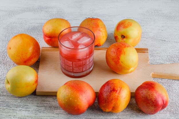 Nectarinas con jugo de alto ángulo de vista en la mesa de tabla grungy y corte