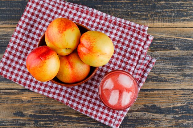 Nectarinas con jugo en un tazón sobre papel de cocina y madera