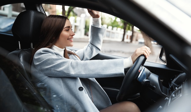 Negocio. Busiensswoman feliz conduciendo coche y agitando la mano a un amigo