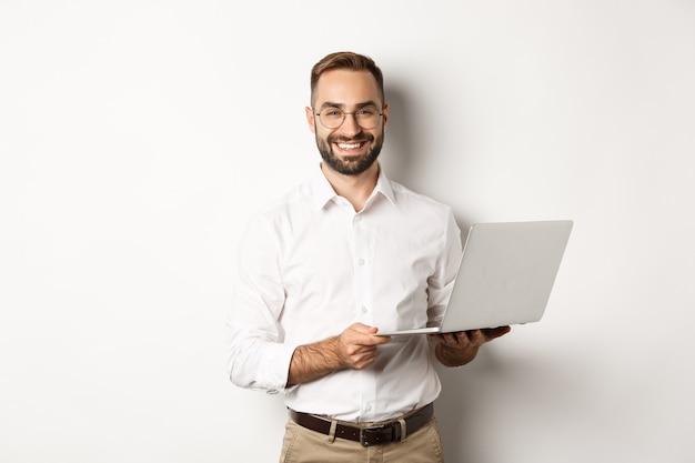 Negocio. Hombre de negocios exitoso trabajando con ordenador portátil, usando la computadora y sonriendo, de pie