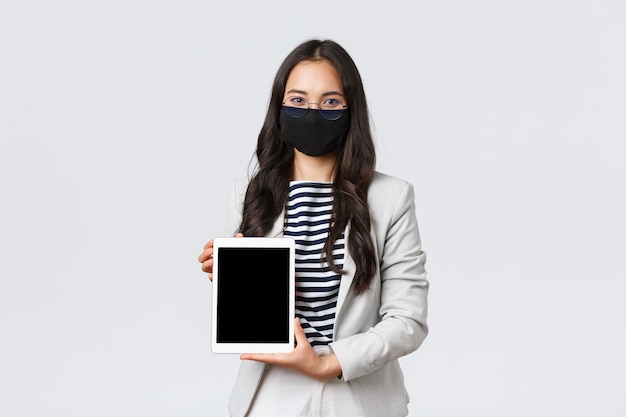 Negocios, finanzas y empleo, covid-19 previniendo el virus y el concepto de distanciamiento social. Agente de bienes raíces femenino confiado que muestra un trato para el cliente en la pantalla de la tableta digital, use mascarilla