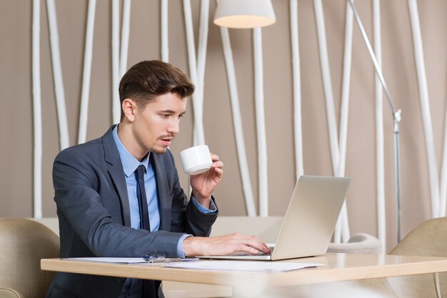 De negocios que trabaja en la computadora portátil y beber café