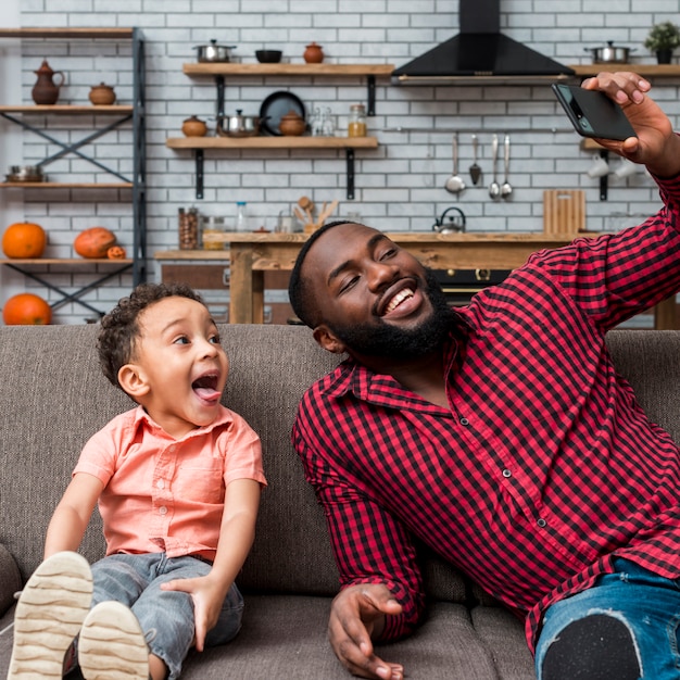 Negro alegre padre e hijo tomando selfie