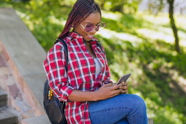 Negro chica viendo el teléfono en el parque