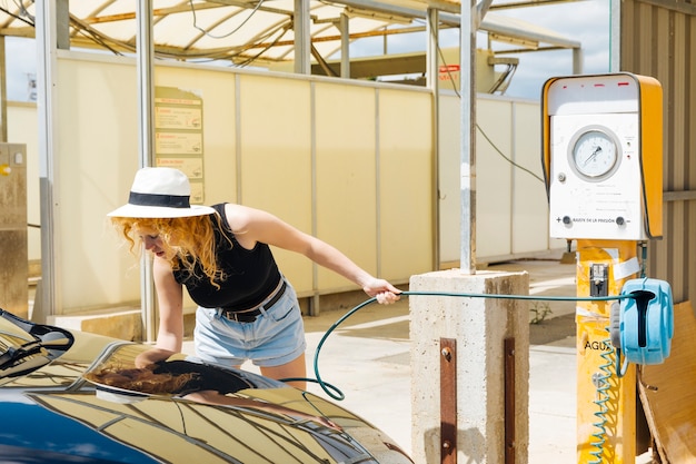 Neumáticos de coche de bombeo femeninos jovenes en la gasolinera