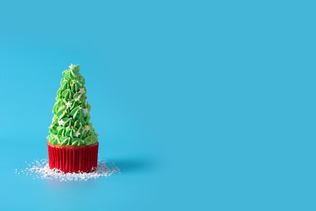 Nevando en cupcakes de árbol de Navidad aislado sobre fondo azul.