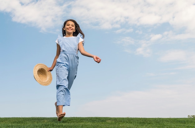 Ángulo bajo alegre niña corriendo sobre hierba