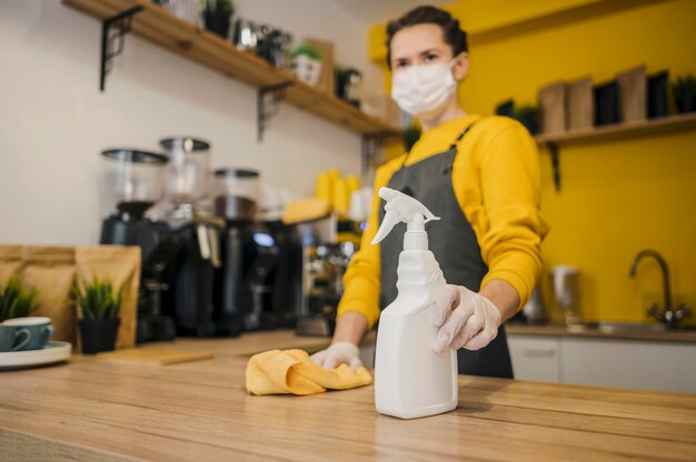 Ángulo bajo de barista femenina con máscara médica