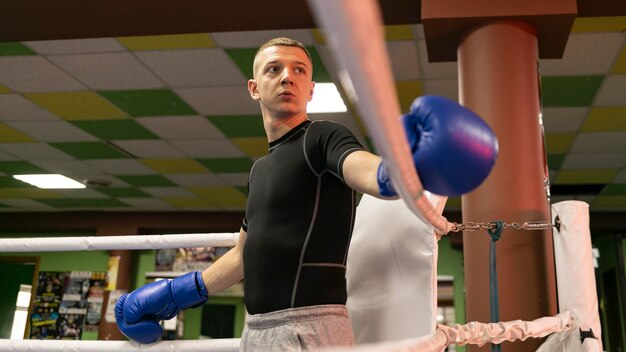 Ángulo bajo de boxeador masculino con guantes en el ring