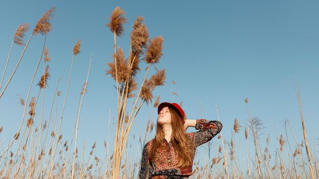 Ángulo bajo de hermosa mujer bohemia posando en la naturaleza