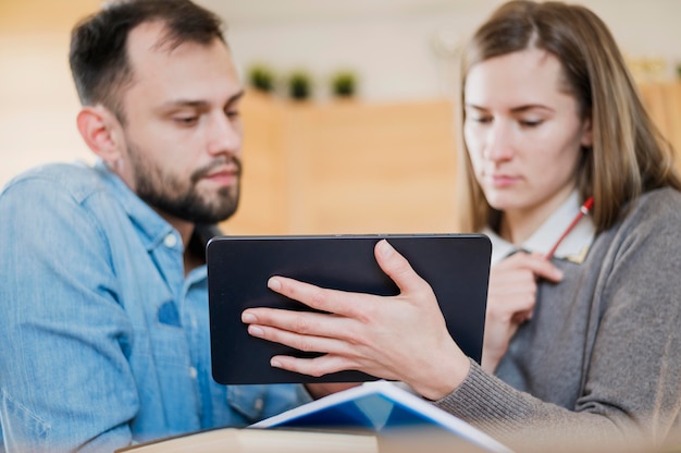 Ángulo bajo de hombre y mujer aprendiendo en casa de la tableta