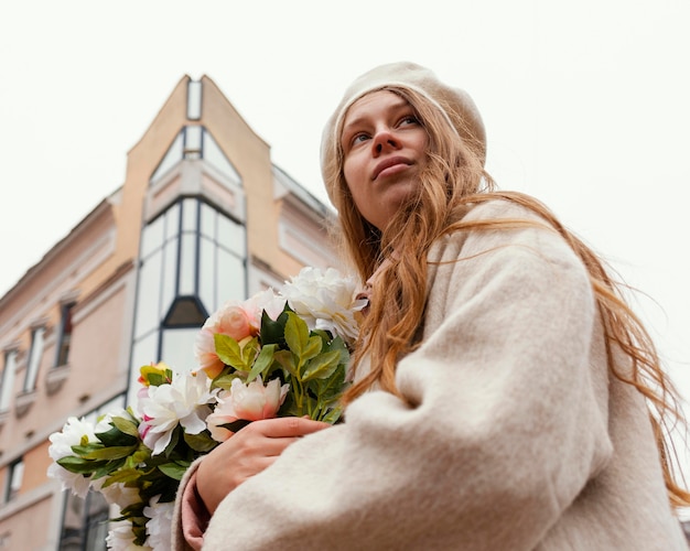 Ángulo bajo, de, mujer, aire libre, tenencia, ramo de flores, en la primavera