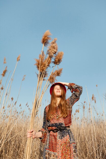 Ángulo bajo de mujer bohemia posando en la naturaleza