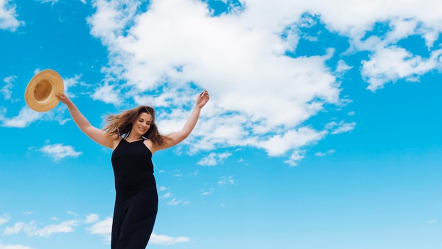 Ángulo bajo de mujer disfrutando de un hermoso día con cielo y nubes