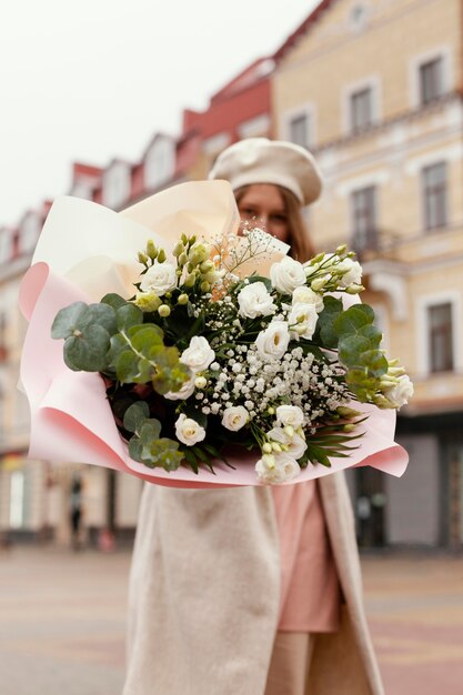 Ángulo bajo de mujer elegante al aire libre con ramo de flores en la primavera