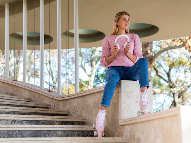 Ángulo bajo de mujer en patines con auriculares