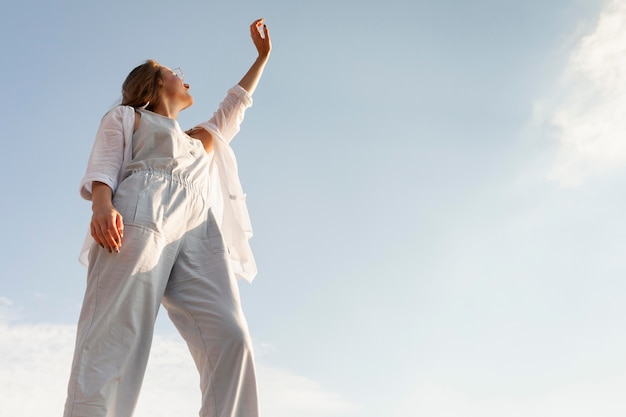 Ángulo bajo de mujer posando bajo el sol con cielo despejado