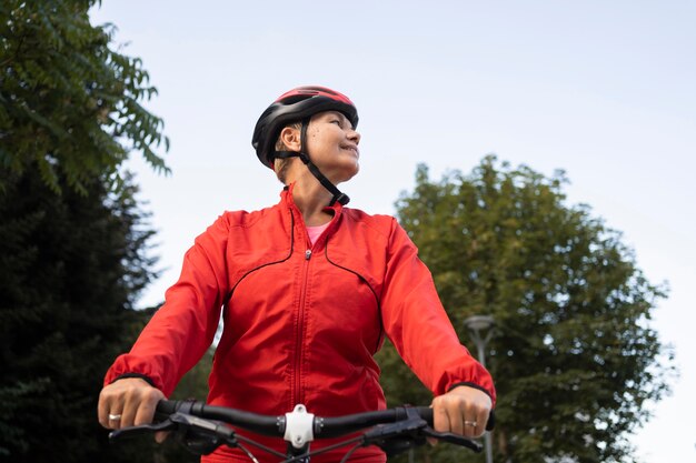 Ángulo bajo de mujer senior en bicicleta al aire libre