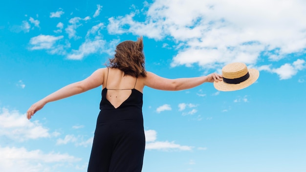 Ángulo bajo de mujer con sombrero y cielo con nubes