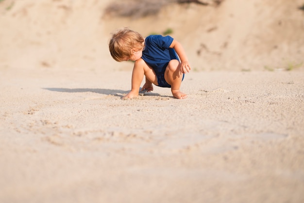 Ángulo bajo, niño pequeño, en la playa, juego