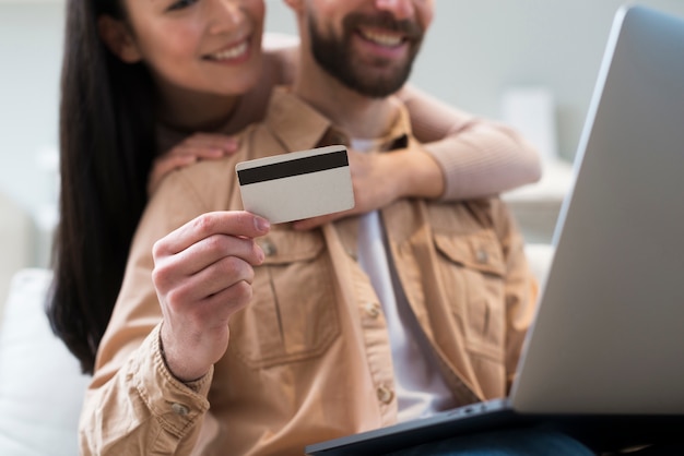 Ángulo bajo de la pareja que compra en línea mientras sostiene la tarjeta de crédito